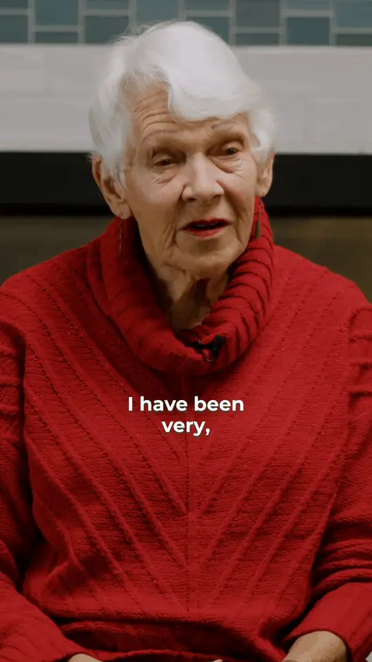Patient story clip: an older woman in a red sweater talks on camera. Burned-in captions read: I have been very, very pleased with the difference.